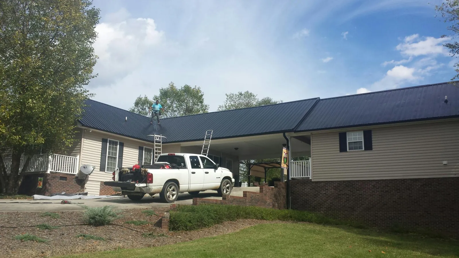 Black metal roof over a home and attached breezeway with ladders set in Wilmington